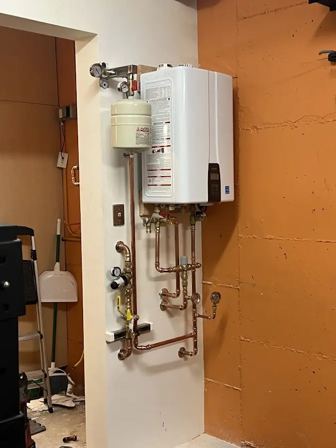 Plumbing technician inspecting water heater connections in Brooks